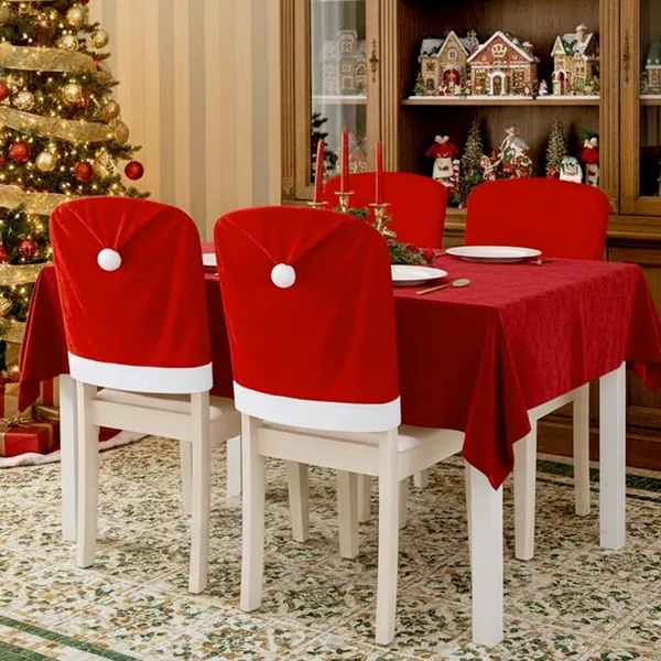 Santa hat chair back covers on dining chairs beside a decorated Christmas tree