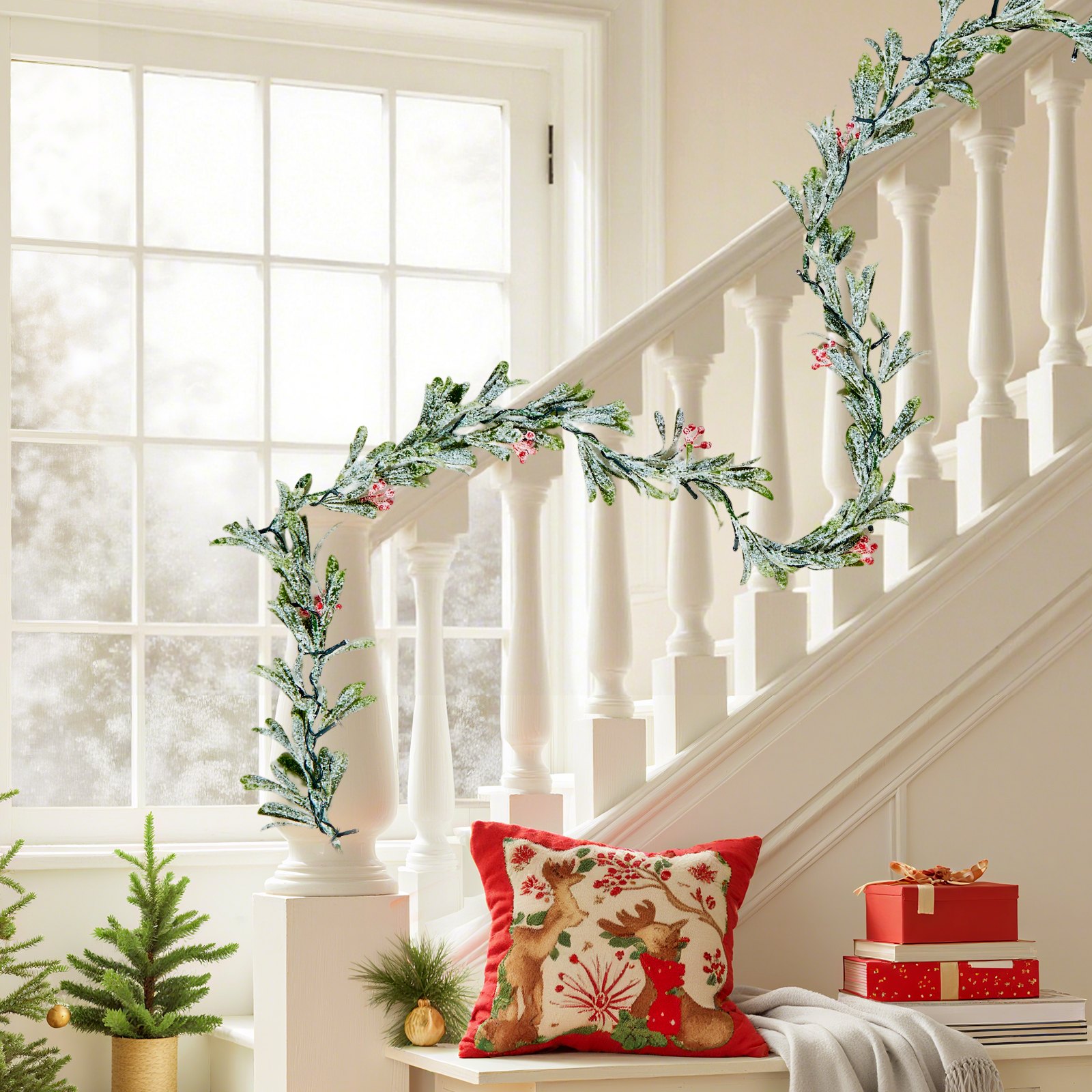 Olive leaf Christmas garland with red berries draped along a white staircase banister