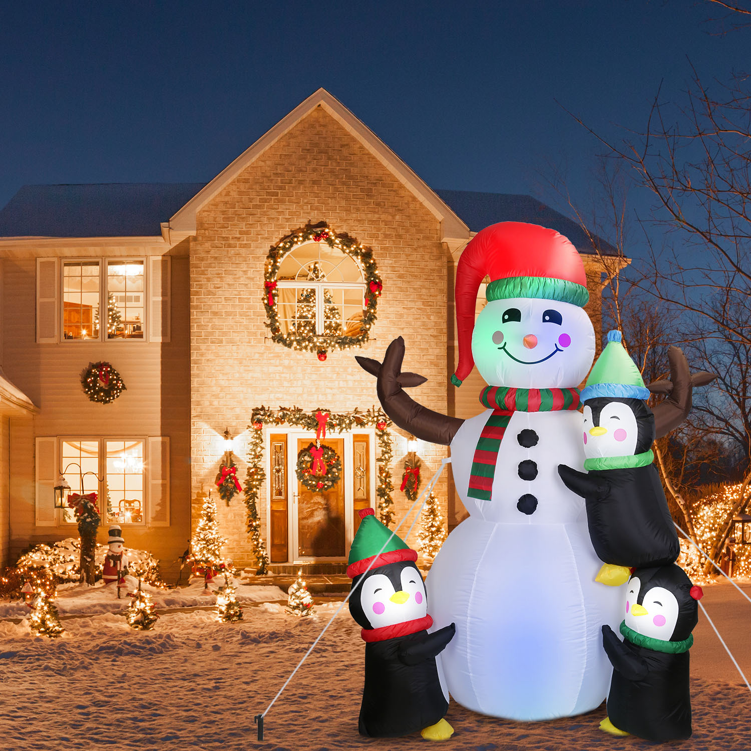 Inflatable snowman flanked by penguins, lit for the yard, view 2